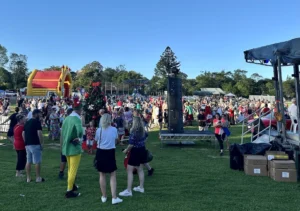 Sundale Community Christmas Carols event with festive crowd enjoying activities.