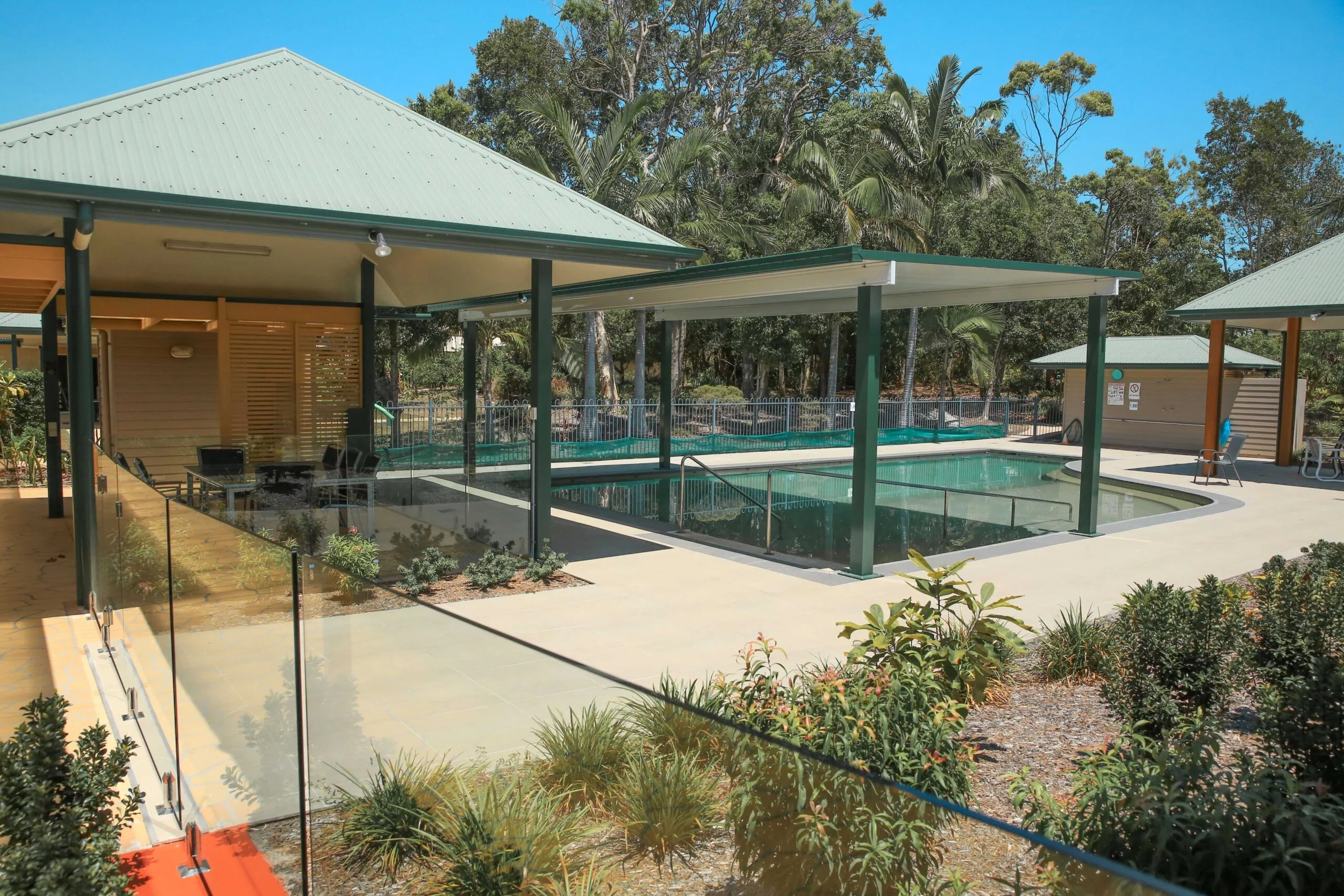 Bright outdoor pool area at Sundale retirement community with shaded seating.